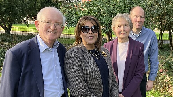 Four of Epping Forest's Liberal Democrat councillors standing on grass with council offices in Epping behind