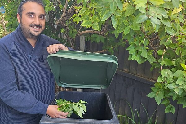 Rahim Hussein puts weeds into an Epping Forest District Council green waste wheelie bin