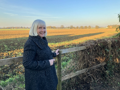 Councillor Lesley Paine stands by a sunlit field near Lower Sheering, Epping Forest