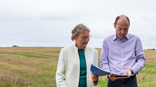 Janet Whitehouse and Jon Whitehouse studying masterplan plan with field in the background