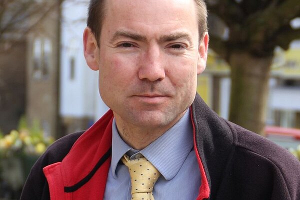 Head and shoulder photo of Jon Whitehouse in blue short with yellow tie