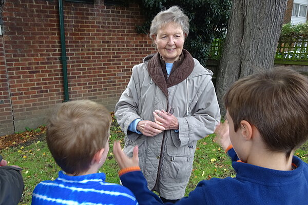 Janet Whitehouse listening to two young children outside a house