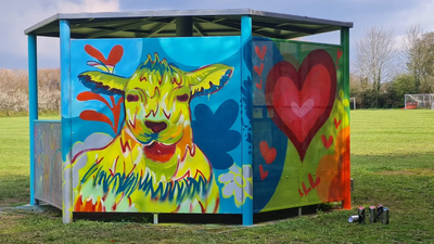 Photo of rain shelter for teenagers with brightly coloured decorative "graffiti" of a bright yellow animal with hearts and flowers
