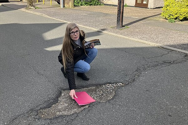 Mandy Gerge measuring the size of a pothole with a clipboard